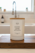 Bottle of coconut colada candle on a wooden surface with a blurred background