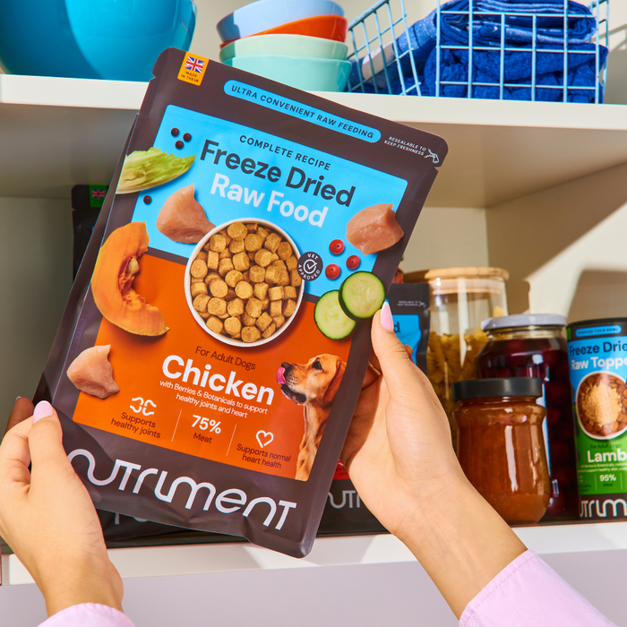 Person holding Freeze Dried Food - Lamb 225g, showcasing its freeze drying process in front of a pantry shelf.