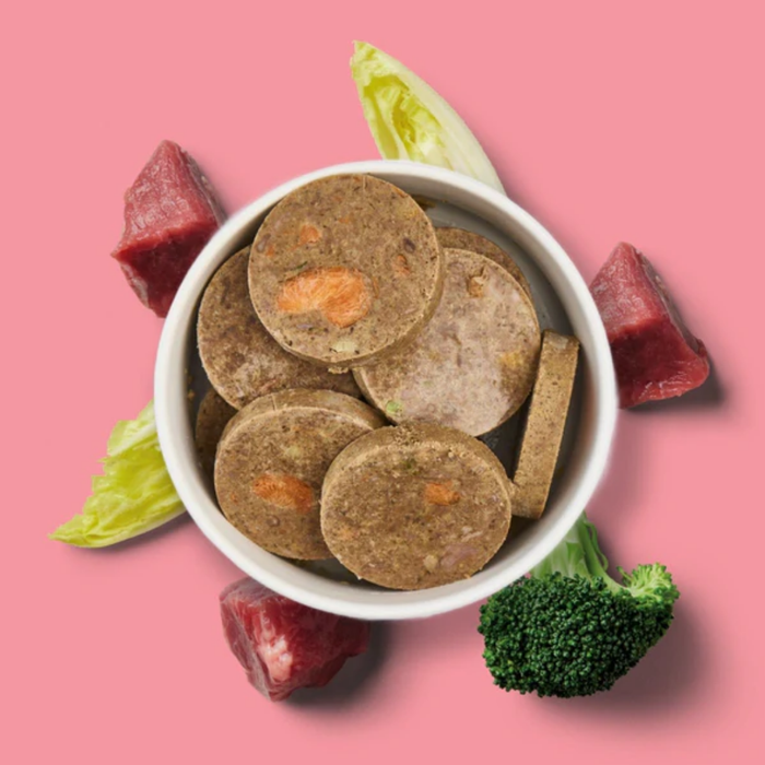 Fresh Medallions - Beef 800g: Grain-free dog food patties with beef, lettuce, and broccoli on a pink background.