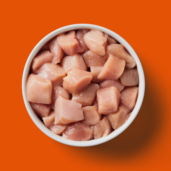 A white bowl of Ultimate Cat Dad Box premium raw cat food sits on an orange background.